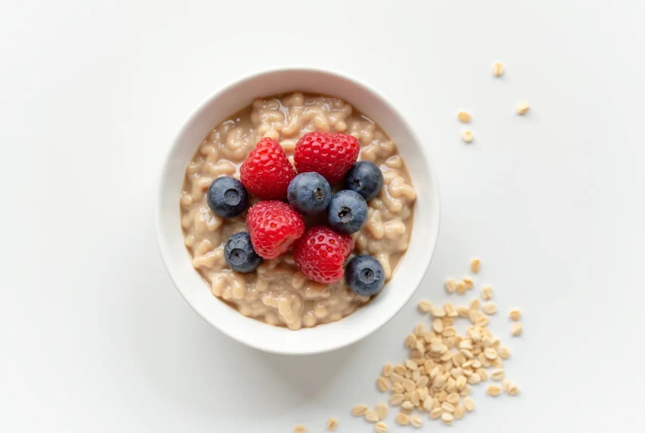 An overhead flat-lay of heart-healthy foods — oats, beans, nuts, olive oil and salmon — on a neutral surface