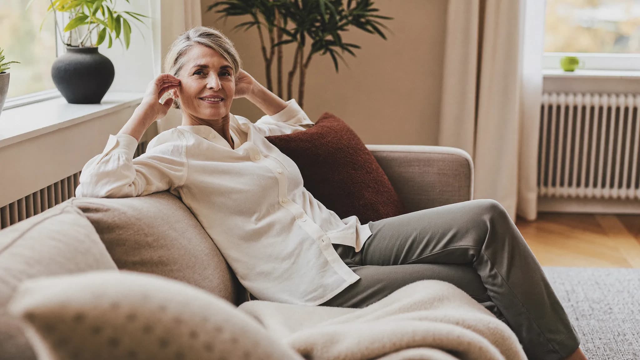 A woman in her late forties relaxing comfortably at home in soft light.